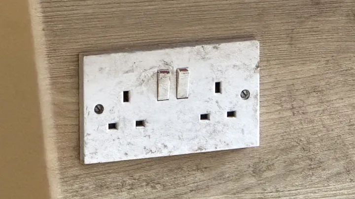 A double BS 1363 socket outlet with two switches, set into a wooden surface